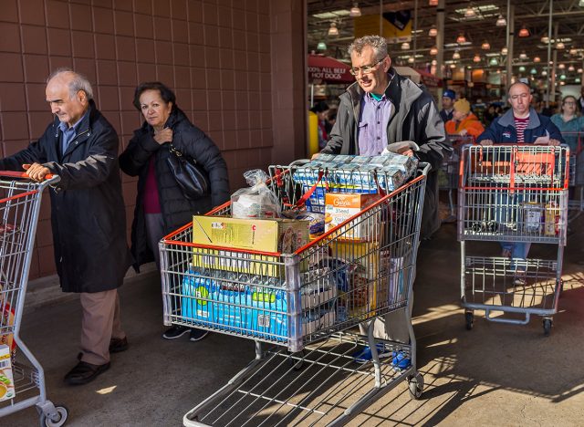 People with shopping carts filled with groceries walking out of Costco store