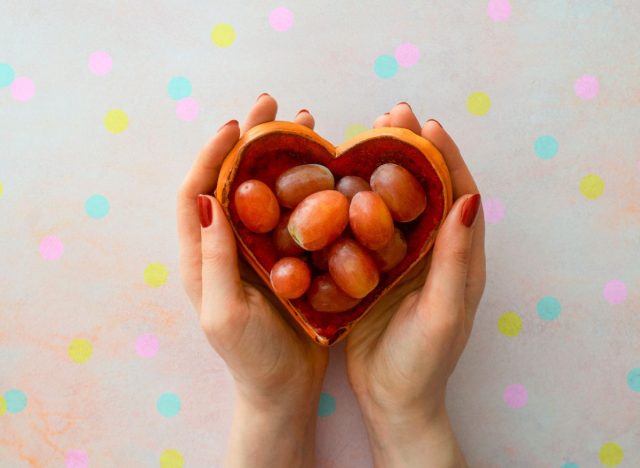 woman holding heart-shaped bowl of grapes