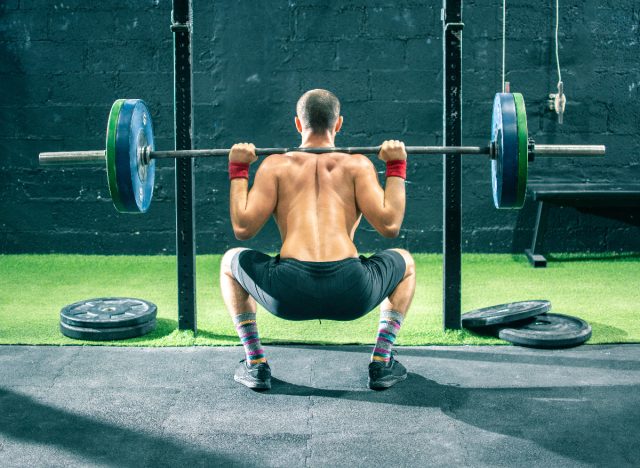 fit man doing barbell back squats