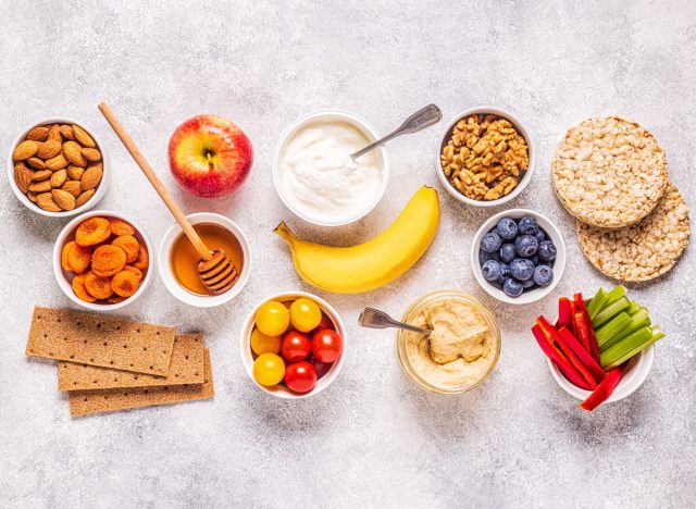 assortment of healthy snacks of nuts fruit apple banana berries vegetables rice cakes