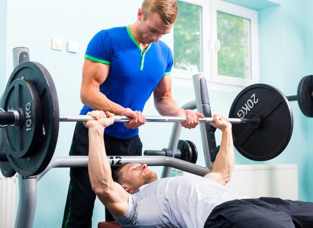 man doing assisted barbell bench press