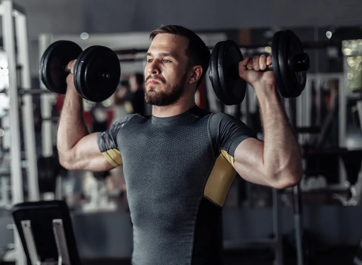 fit man doing dumbbell exercises for a tapered waist at the gym