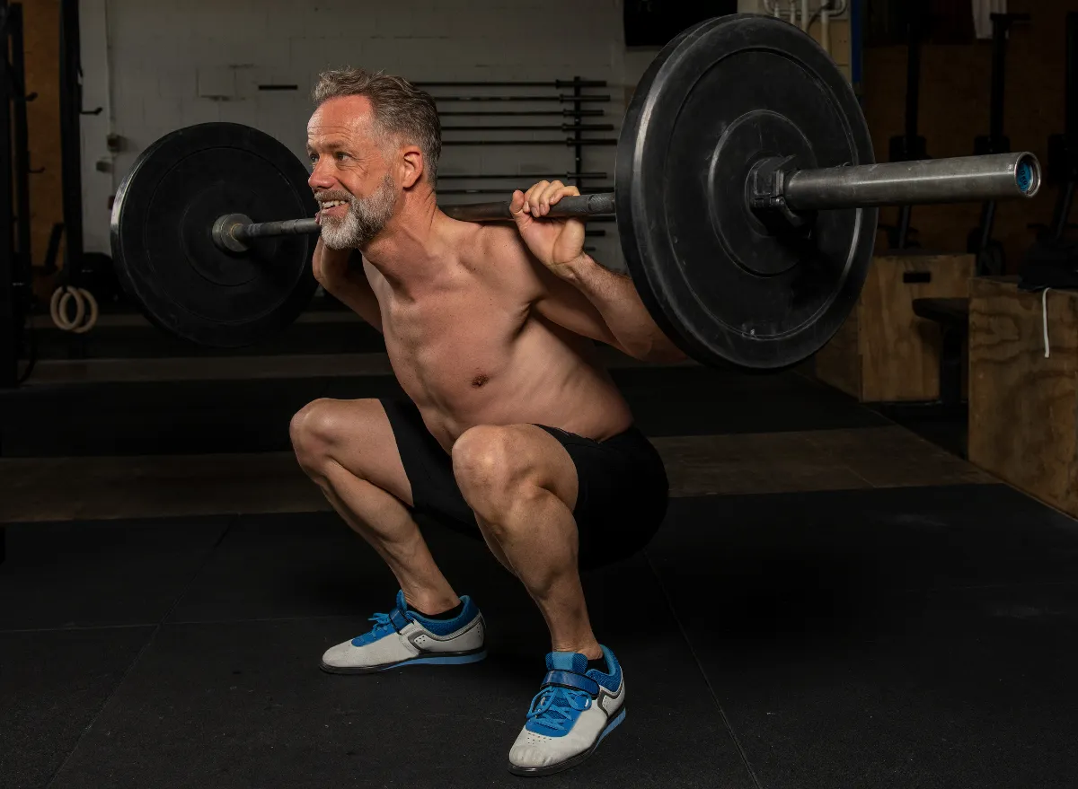 man performing heavy loaded barbell squats, concept of exercises that are too hard on knees after 50