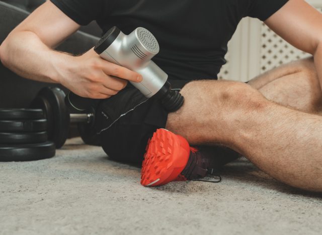 man using massager to massage leg after workout