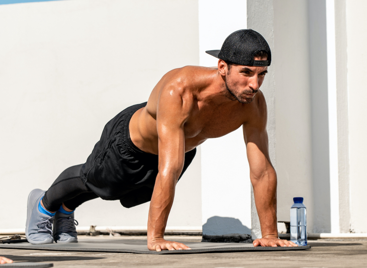 Young Man Use Dumbbell Exercises Chest Fly on Yoga Mat in Living