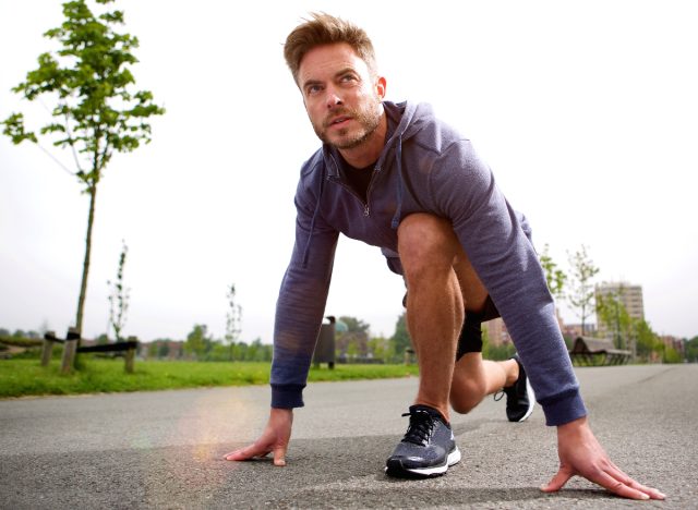 middle-aged man gearing up to sprint, concept of fitness habits that destroy your body after 40