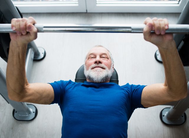 mature man doing barbell bench presses, concept of fitness habits that destroy body after 60