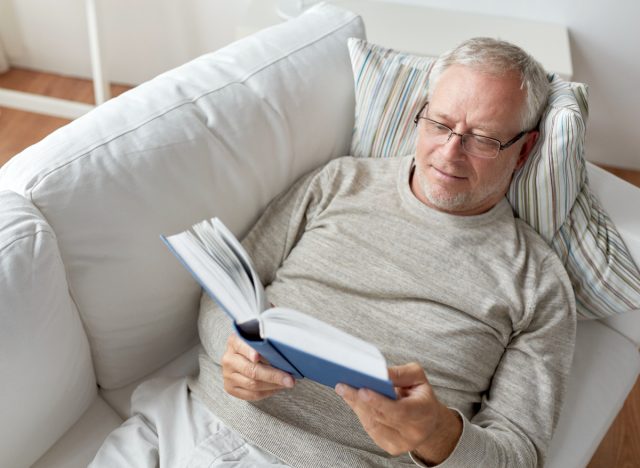 mature man reading book on couch