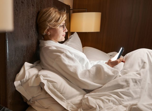 mature woman texting in bed