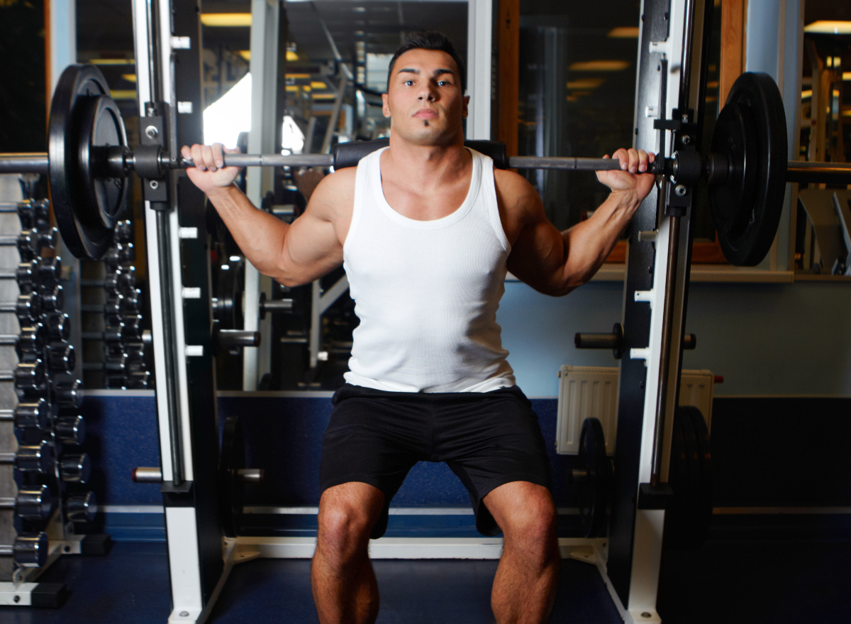 muscular man doing barbell squats as part of hypertrophy workout to build size and strength