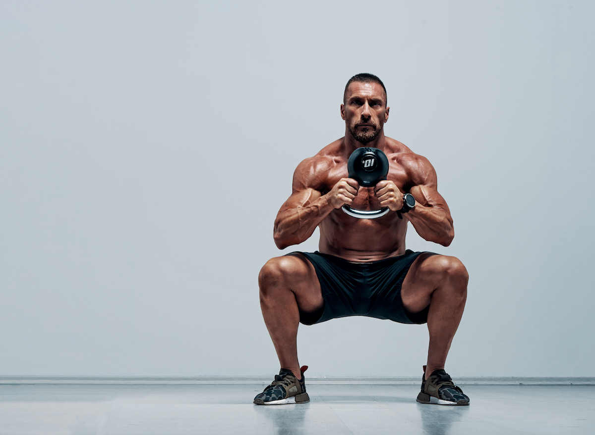 muscular man doing kettlebell squats, concept of daily exercises for men to maintain muscle