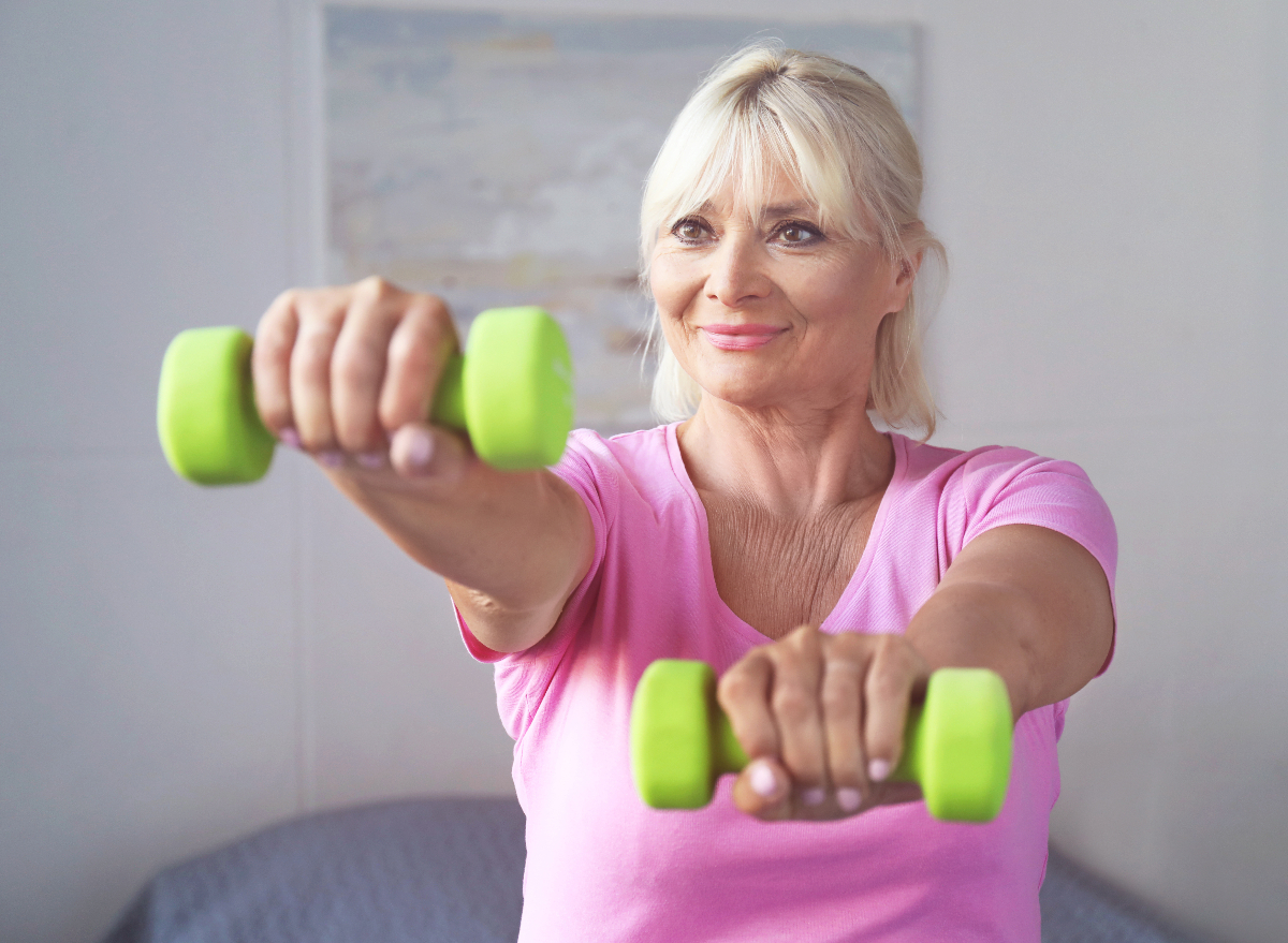 older woman doing chicken wings workout with dumbbells to tone arm flab