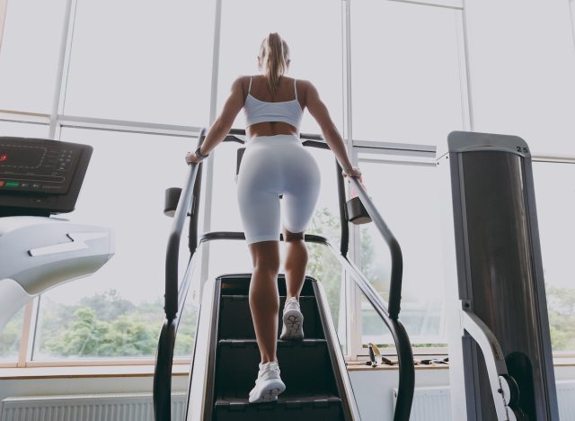 fitness woman doing StairMaster exercise in gym, back view