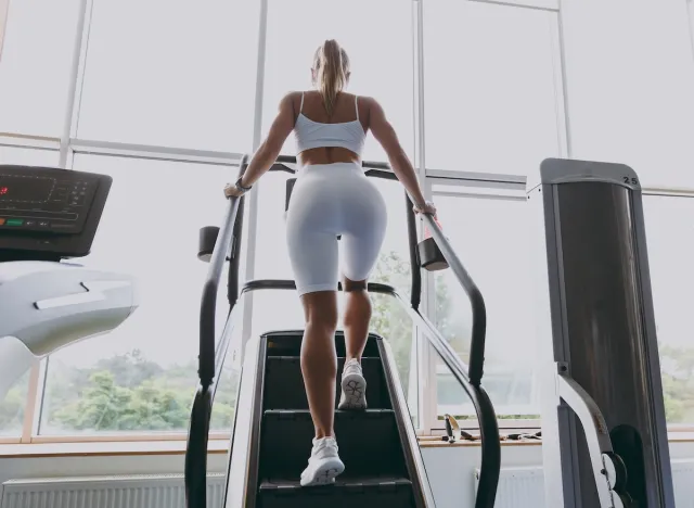 fitness woman doing StairMaster workout at gym, back view