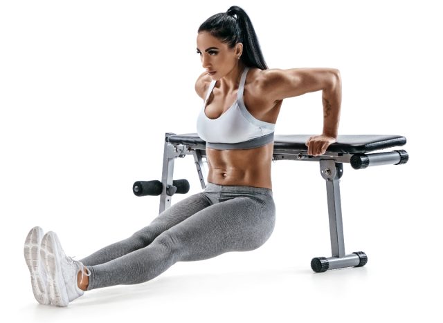woman white background doing tricep dips on workout bench