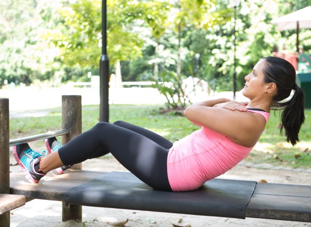 woman doing sit-ups outdoors, concept of the worst exercises to lose belly fat