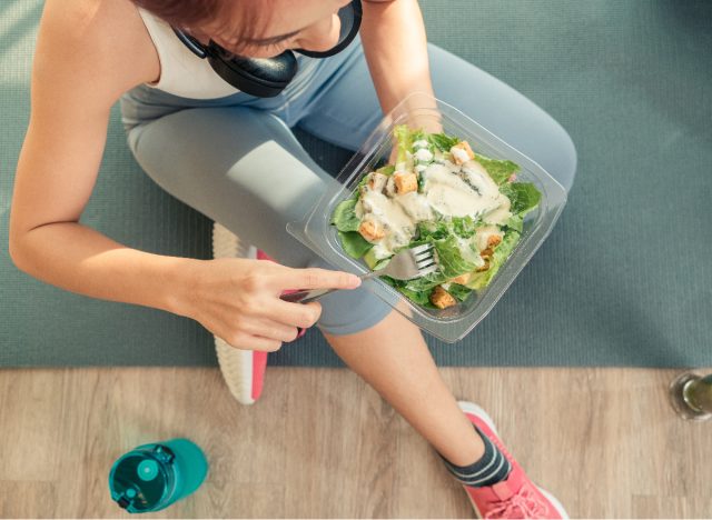 kvinna som äter sallad på yogamatta, koncept med att förbereda måltider i förväg för att snabbt gå ner fem pund