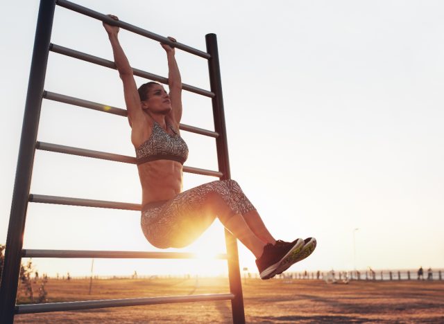 fit woman doing hanging knee raises, concept of strength exercises for women to get instant abs