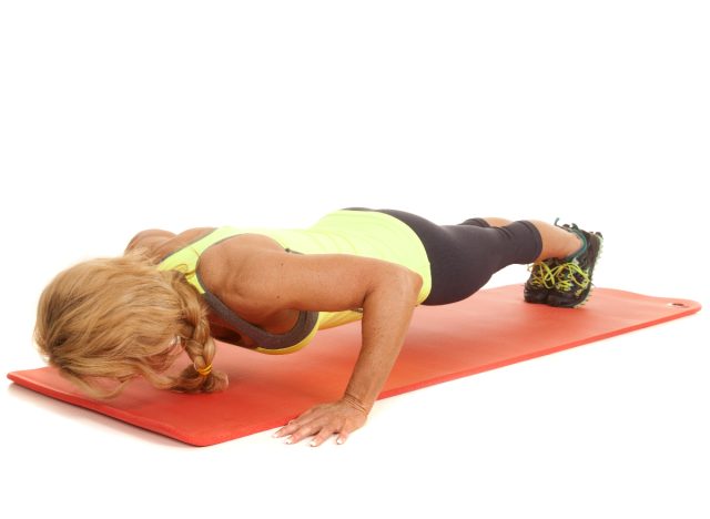 woman doing pushups on workout mat, white background