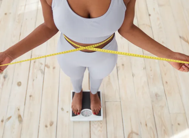 woman measuring waistline, on scale, concept of tips to lose 10 pounds in one month