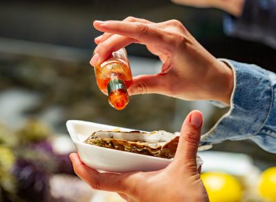 Pouring hot sauce on an oyster