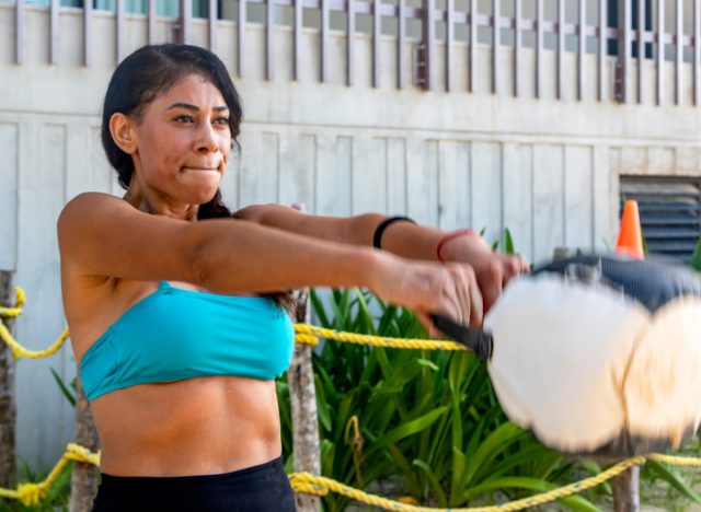 woman doing kettlebell/weighted swings, concept of quick daily exercises to melt body fat