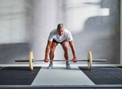 mature man doing barbell exercise, concept of strength exercises for men in their 50s