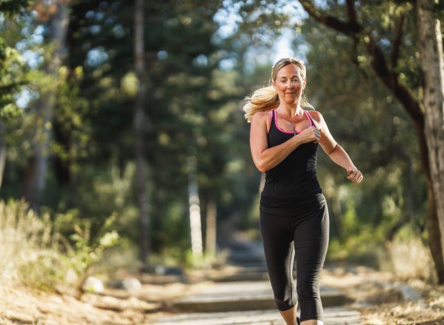 middle-aged woman jogging or running outdoors, concept of workout to lose body fat in your 40s