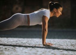 woman doing pushups, concept of a no-gym workout to melt belly fat