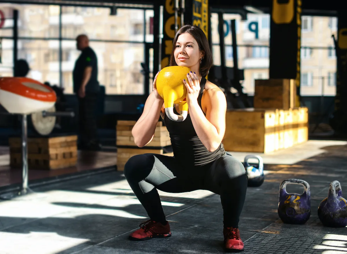 woman doing kettlebell goblet squats weight training exercises for weight loss at the gym