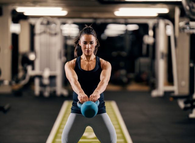 fit woman doing kettlebell swings, concept of exercises to lose inches off your waist in 30 days