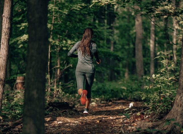 woman running through woods getting exercise on trail