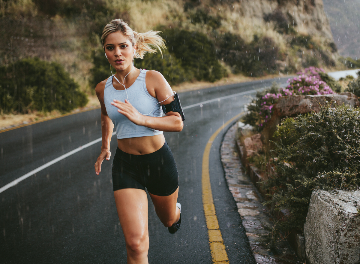 fit woman running outdoors in the rain, concept of exercises to melt visceral fat