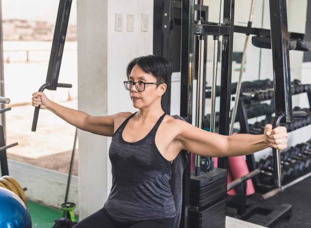 Woman uses arm exercise machine in gym