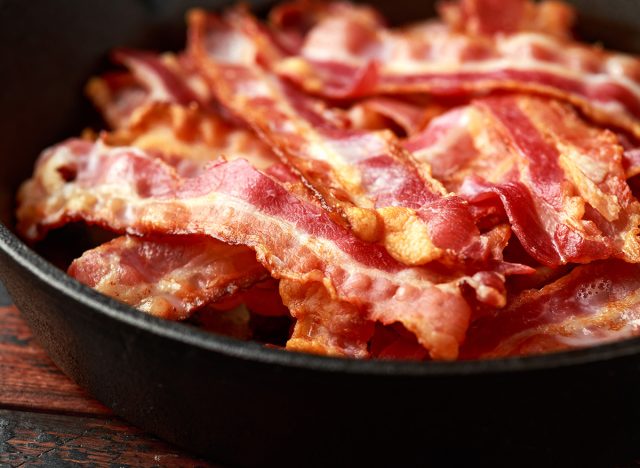 Fried crunchy Streaky Bacon pieces in a cast iron skillet