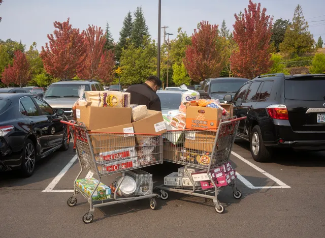 Customer with two full shopping carts loads his car at Costco