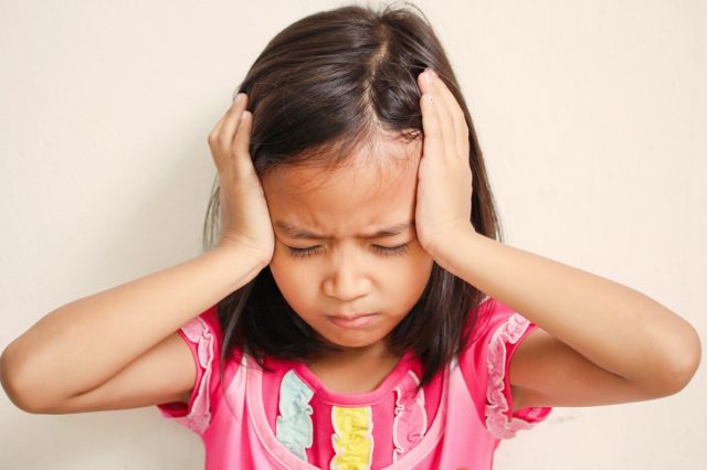 Portrait of preschooler girl having a headache