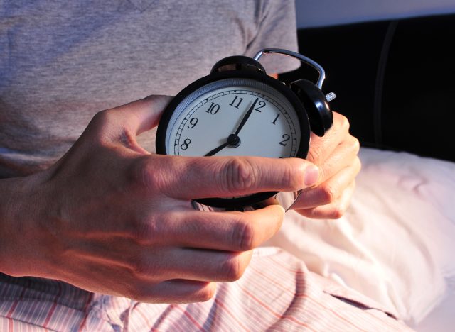 close-up man setting alarm before bed