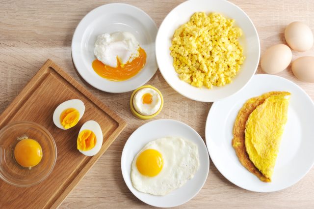 Various ways of cooking chicken eggs. Omelette, poached, soft-boiled, hard-boiled, fried, scrambled eggs. Top view. Close-up.