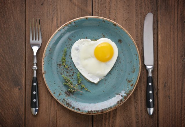 Fried egg in shape of heart on blue plate