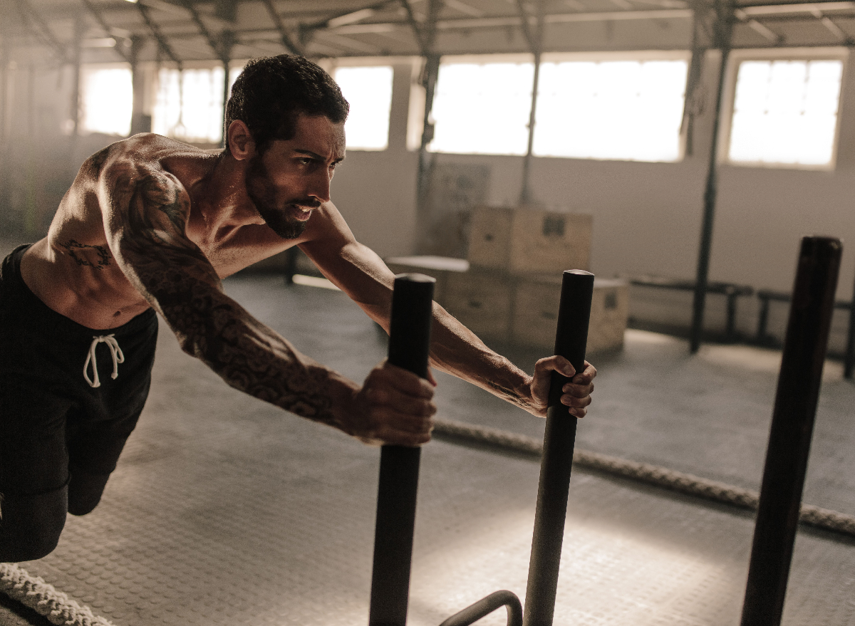 fit man doing sled push exercise, concept of exercises to increase endurance and stamina