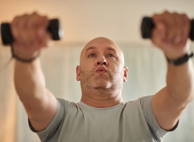 homme d'âge moyen soulevant des haltères, concept d'entraînement hebdomadaire pour développer l'endurance musculaire après 40 ans