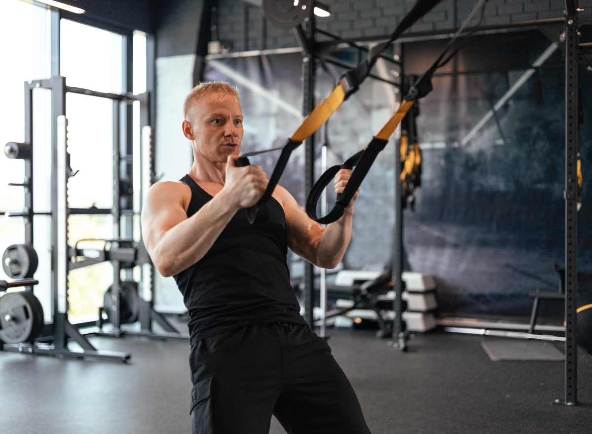 fit man working out with TRX straps, concept of workouts to maintain muscle tone in your 40s