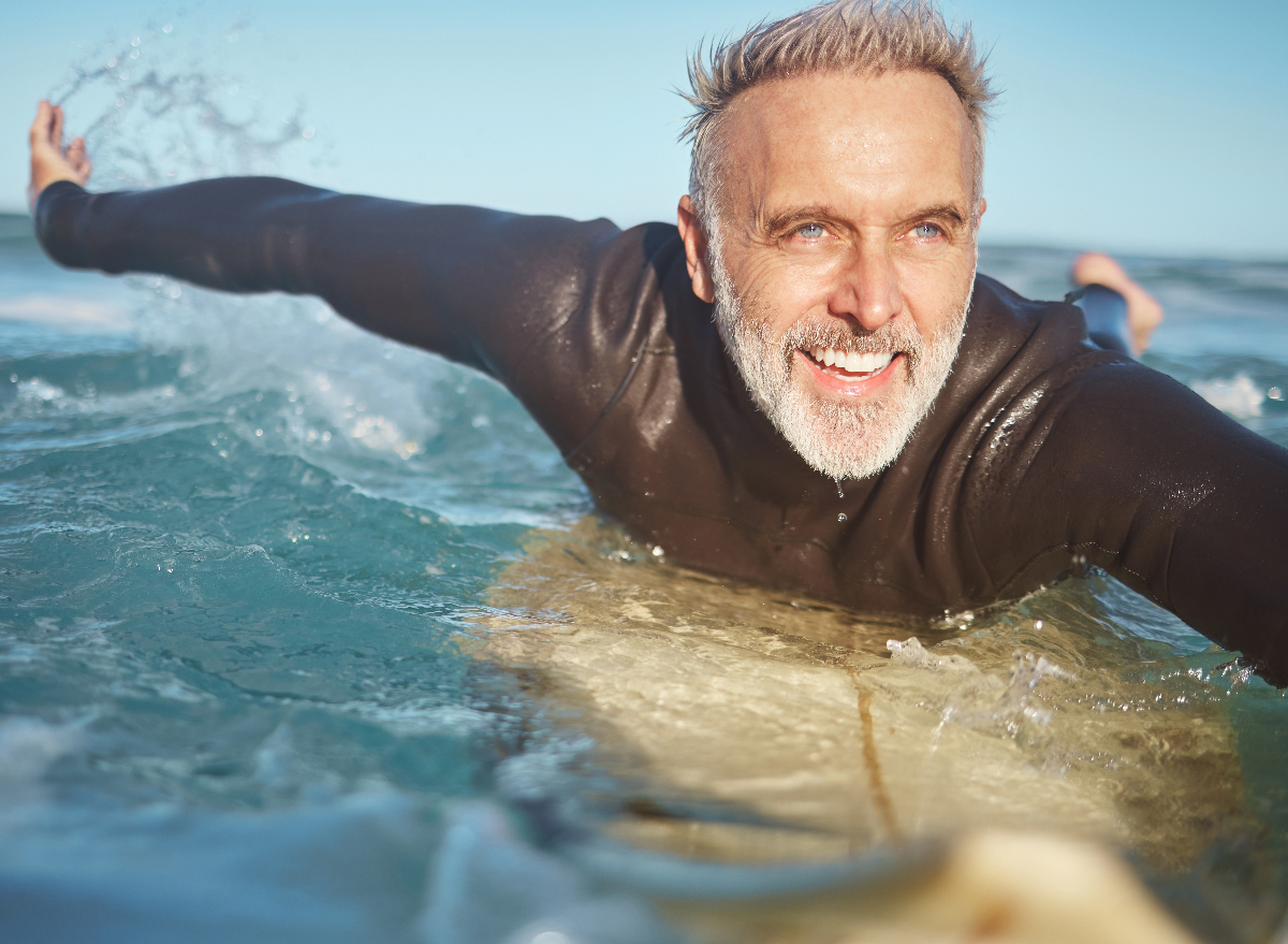 mature healthy man surfing, concept of habits to live longer