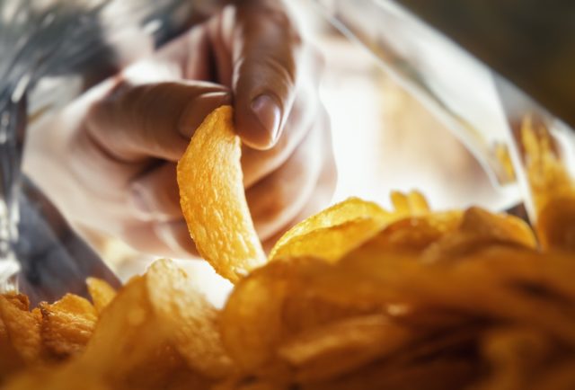 Hand takes out potato chips inside the package