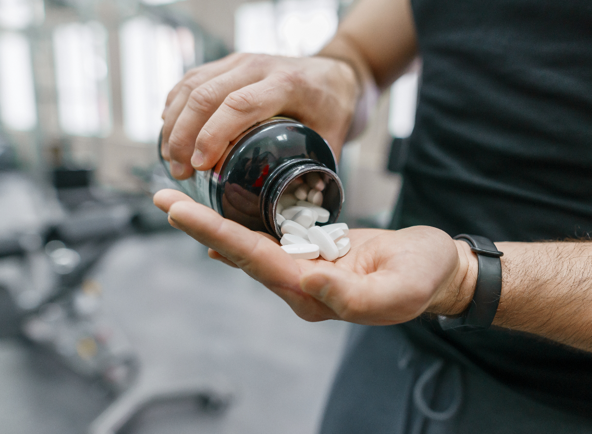 close-up man pouring bottle of supplements into hand at gym, concept of the worst supplements for muscle growth