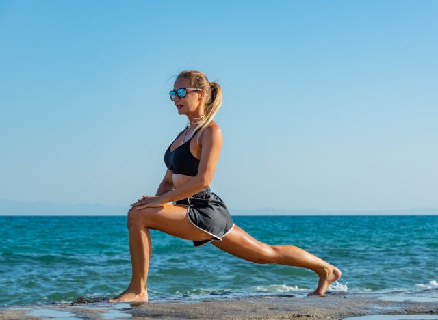 woman lunges along beach, concept of no-equipment exercises to slim down in four weeks