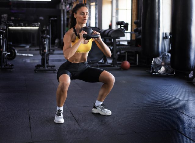 fit woman doing kettlebell squats