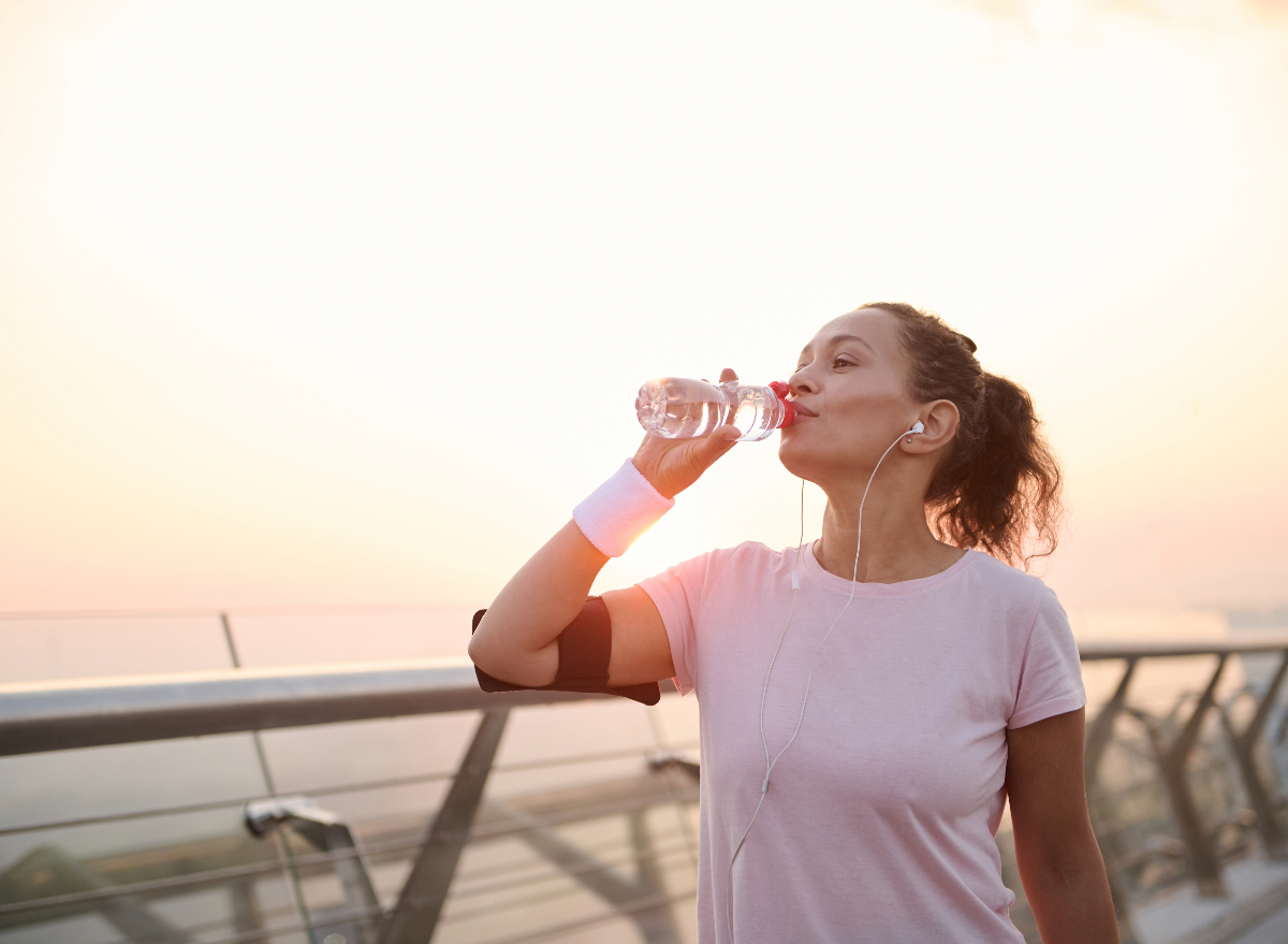 woman drinking bottled water while on walk outdoors, concept of how to lose 10 pounds without dieting