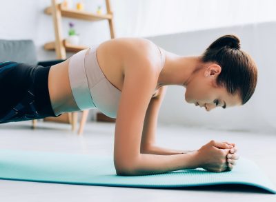 woman doing forearm planks, concept of ab exercises to melt belly fat